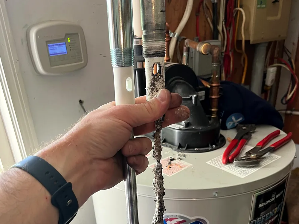 Old anode rod being pulled from a hot water tank